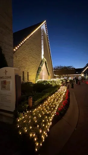 Roof peak lighting above a lit hedge line along a front walkway