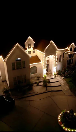Elevated view of a home's lit gables and walkway lighting at night