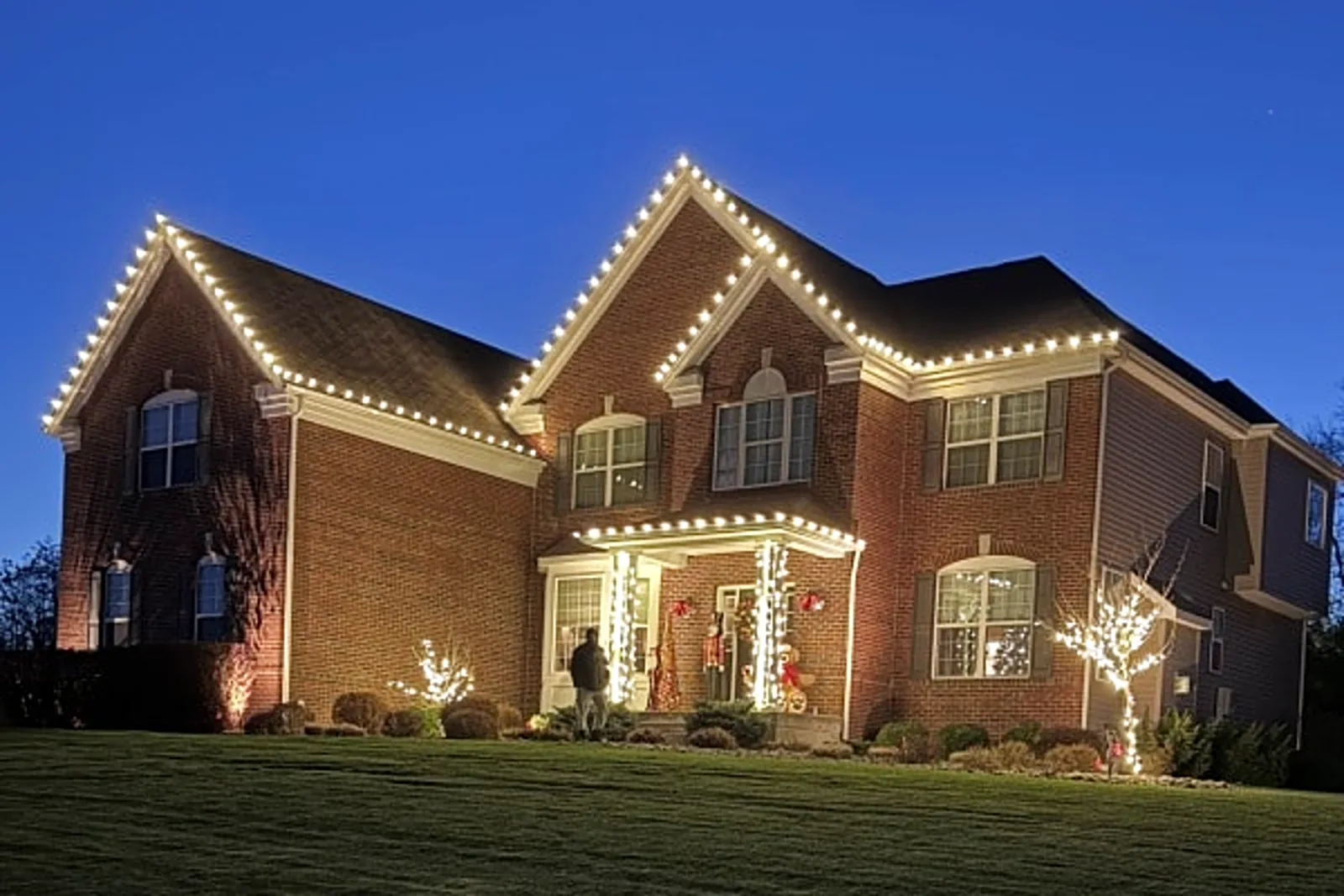 Home with balanced professional Christmas lighting on rooflines and trees