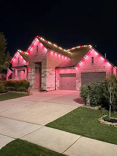 Home front with bold red roofline and garage lighting at night
